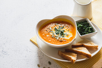 Vegetarian autumn pumpkin and carrot soup with cream and seeds. Comfort food, fall and winter healthy slow food concept