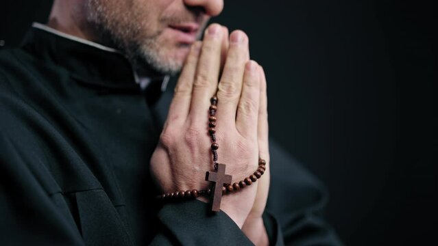 Priest reading gospel with praying beads in hands, religious service in church