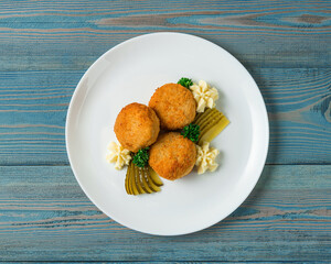 Fish nuggets with potatoes puree served on a white plate on a rustics blue background