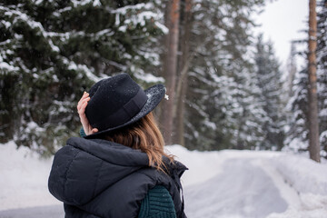 Caucasian young woman in black hat in winter snowy forest.