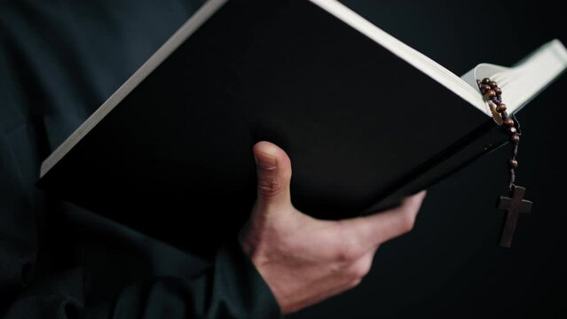 Close-up priest's hands turning pages of Bible book, religious service sacrament