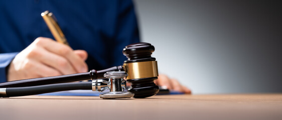 Gavel With Medical Stethoscope On Wooden Desk