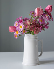 pink flowers in white jug on background gray wall