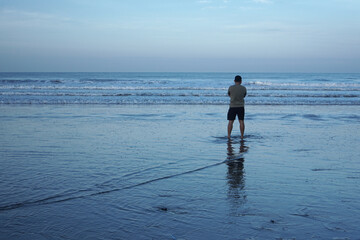 A man standing alone on the beach in the morning                  