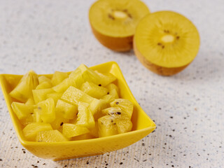 Golden kiwifruit chopped chunks in a bowl. Fresh kiwi fruit salad snack.