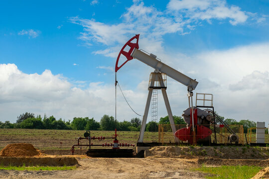 Oil field site, in the oil pumps are running. Silhouette of beam pumping unit