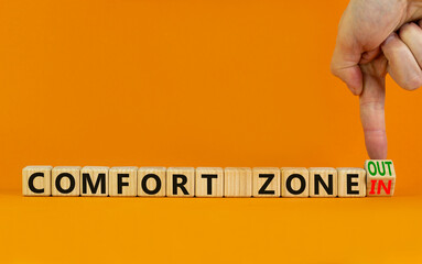 Out or in comfort zone symbol. Businessman turns wooden cubes and changes words Comfort zone in to Comfort zone out. Beautiful orange background, copy space. Business, psychology comfort concept.