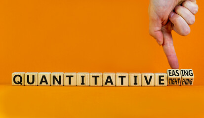 Quantitative easing or tightening symbol. Businessman turns cubes changes words Quantitative easing to Quantitative tightening. Orange background. Business quantitative easing or tightening concept.