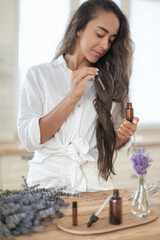 Essential oils of lavender in a glass dark bottle. The girl cares for the skin and hair. Scandinavian interior. - 483599948
