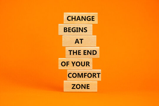Out from comfort zone symbol. Wooden blocks with words Change begins at the end of your comfort zone. Beautiful orange table, orange background, copy space. Business, out from comfort zone concept.