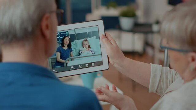 Retired Couple Meeting With Family On Online Videocall, Holding Tablet For Remote Communication. Older Man And Woman Using Device With Video Teleconference To Talk To Relatives. Close Up