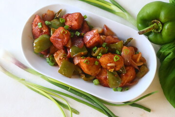Idli Manchurian. An Indo Chinese fusion food made with leftover idlis, capsicum and spring onions. Prepared by cutting leftover idlis into small dumplings