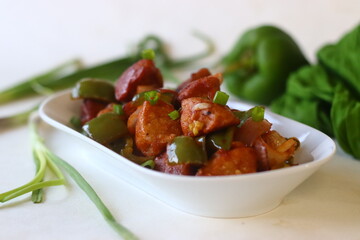 Idli Manchurian. An Indo Chinese fusion food made with leftover idlis, capsicum and spring onions. Prepared by cutting leftover idlis into small dumplings