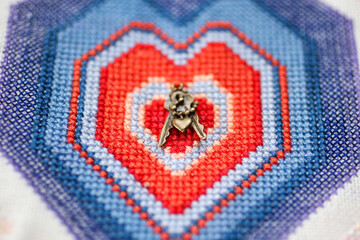 Closeup of a embroidery heart with miniature keys. Top view. Love concept background - obrazy, fototapety, plakaty