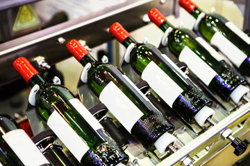 Winery. Production of alcoholic beverages and bottling in glass bottles on a conveyor line. Close-up
