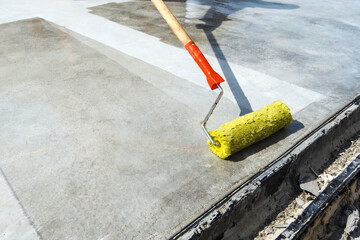 Lacquering of concrete floors. Applying primer to the surface using a brush roller. Close-up