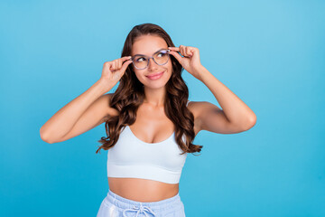 Photo of cheerful cute pretty lady look empty space wear eyeglasses sportswear set isolated blue color background