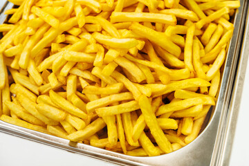 Lots of french fries on a metal tray. Cooking vegetables in vegetable oil. Big plan. selective focus