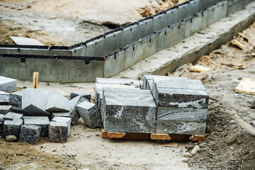 Construction of a drainage system. Concrete gutter and granite pavers are located at the construction site. Selective focus. Foreground