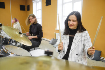 Young adult men and women learn to play drums at school. Hobbies and pastime.