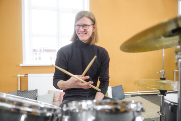 Young adult men and women learn to play drums at school. Hobbies and pastime.
