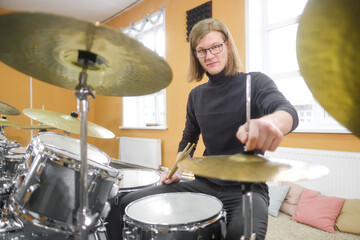 Young adult men and women learn to play drums at school. Hobbies and pastime.