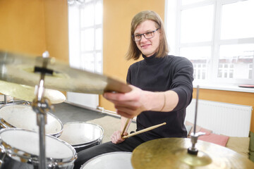 Young adult men and women learn to play drums at school. Hobbies and pastime.