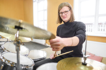 Young adult men and women learn to play drums at school. Hobbies and pastime.