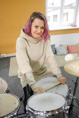 Portrait of a young beautiful adult woman behind a drum kit. Hobbies and pastime.