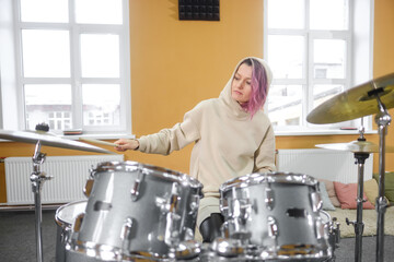 Portrait of a young beautiful adult woman behind a drum kit. Hobbies and pastime.