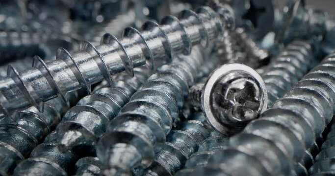 Super macro close up screws, bolts nut and bolt parts, metal springs, fasteners in a heap. Concept Screws for macro, Steel screws. Extreme close up of drilling into wood with screw twisted into place.