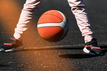 A child is playing basketball outdoors . The girl trains to play on the basketball court .Outdoor training .