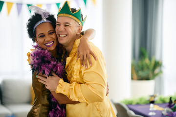 Happy man and his African American friend in Mardi Gras costumes have fun and embrace on a party. - Powered by Adobe