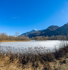Fototapeta na wymiar landscape with frozen lake in winter and blue sky