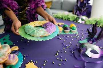 Close-up of woman serving traditional King cake at dining table.
