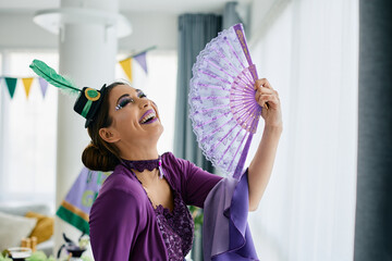 Young cheerful woman in carnival costume has fun during Mardi Gras festival celebration.