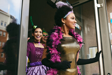 Happy black woman and her friends in carnival costumes going to Mardi Gras parade.