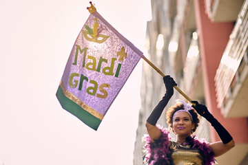 Black woman in carnival costume with Mardi Gras flag on street parade. © Drazen