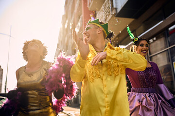 Cheerful friends have fun while dancing on Brazilian carnival parade on the street.