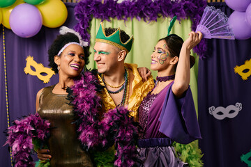 Happy multiracial people in carnival costumes have fun on Mardi Gras celebration party.