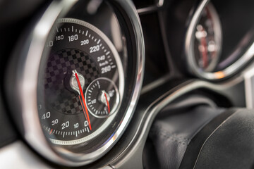 Widok sportowych zegarów z deski rozdzielczej w sportowym samochodzie. Zegary stylizowane na sportowy charakter. Niebieska poswiata odbija błękitne niebo w podróży.