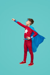 Superhero kid pretending flight against blue background