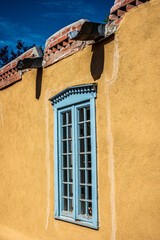 turquoise framed window in an adobe wall