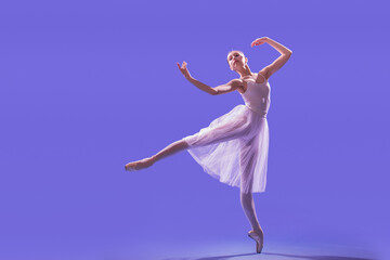 an elegant ballerina in pointe shoes is dancing in a long flying white skirt on a lilac light background