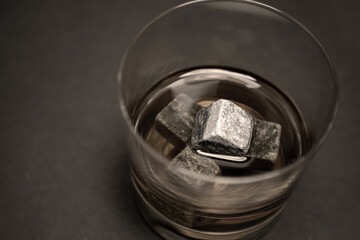 Gray whiskey soapstonestones in the glass. Close up view of whisky stones in the glass with whisky isolated on dark background whith copyspace