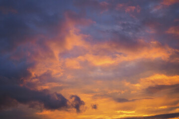 Cloudy sky at sunset. Dark purple-yellow natural background or wallpaper. The rays of the setting...