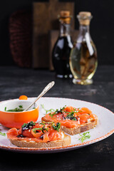 Healthy toasts with salmon, cream cheese,  sesame seeds, black pepper and arugula on plate.