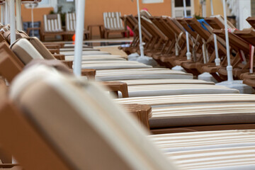 Beautiful brown striped sun beds are lined up with sun loungers. An ideal place to relax and sleep.