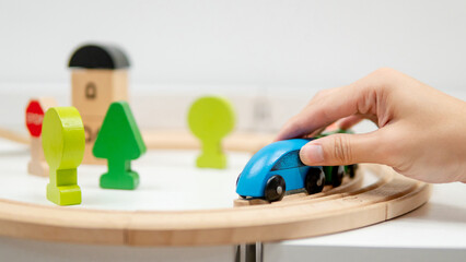 Male hand holding wooden blue car train on railway track for kids. educational logic toys for...