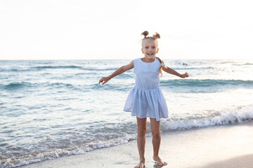 Beautiful happy girl in a blue dress on the seashore,